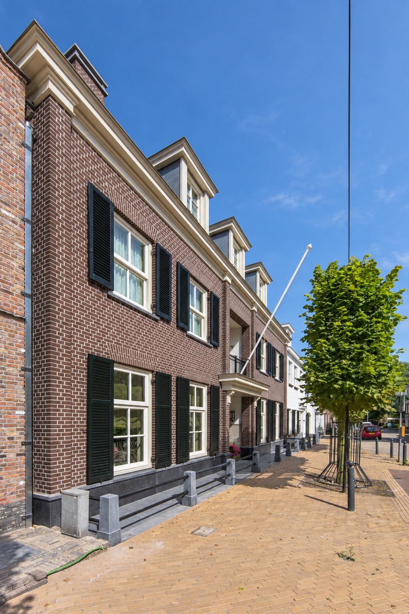 Bakstenen gevel met luiken en lichte kozijnen