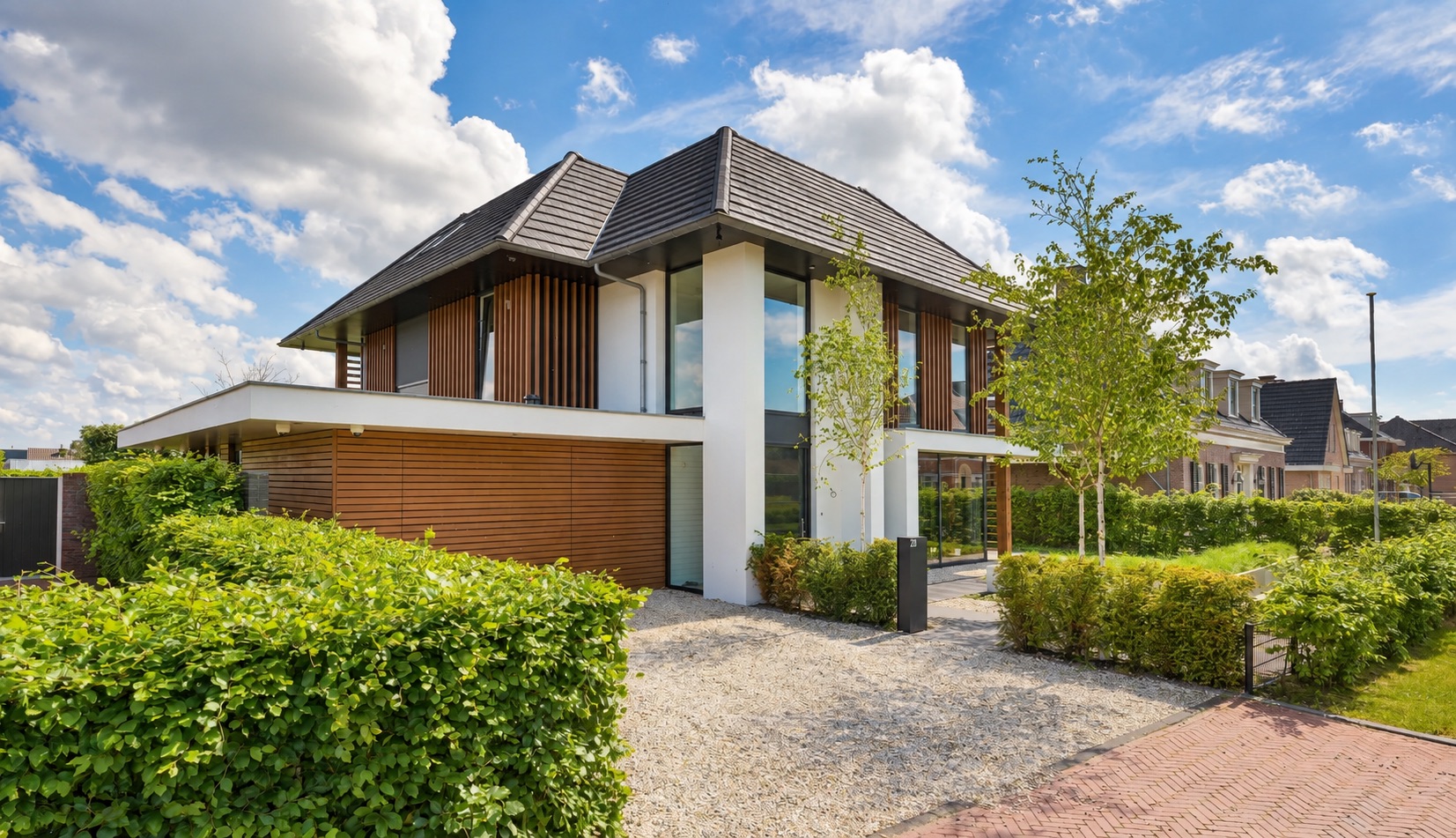 Moderne villa met witte gevelvlakken, houten details en donkere kozijnen