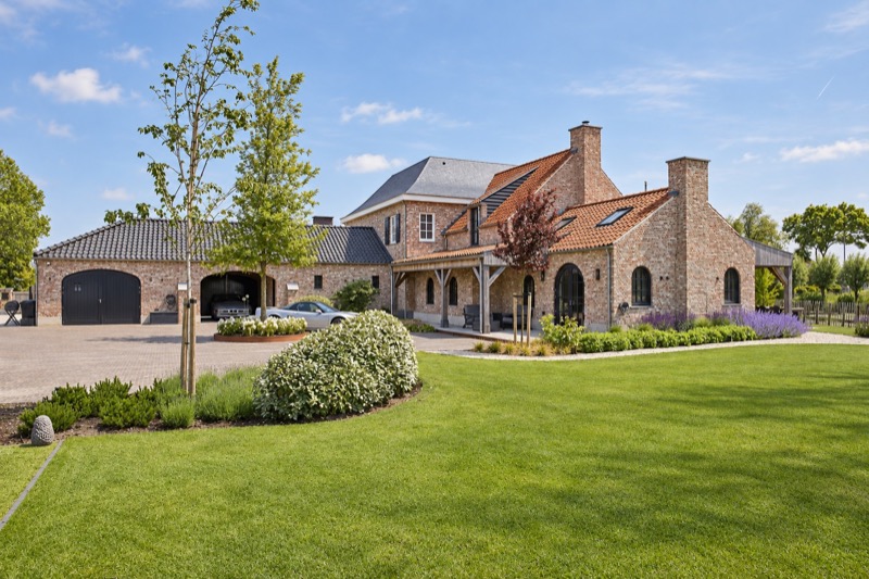 Landelijk woonhuis met garages, bakstenen gevels en een tuin
