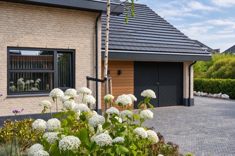 Lichte gevel met donkere kozijnen, garage en houten bekleding